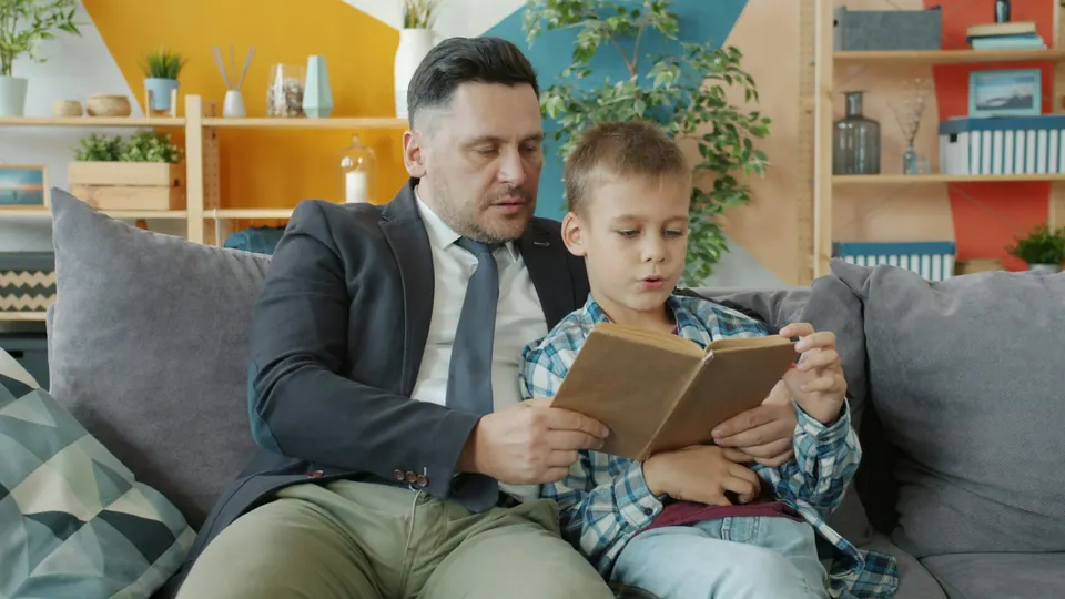 Pai e filho lendo um livro juntos no sofá
